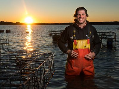An oyster farmer stands hip deep in water near his oyster cages.