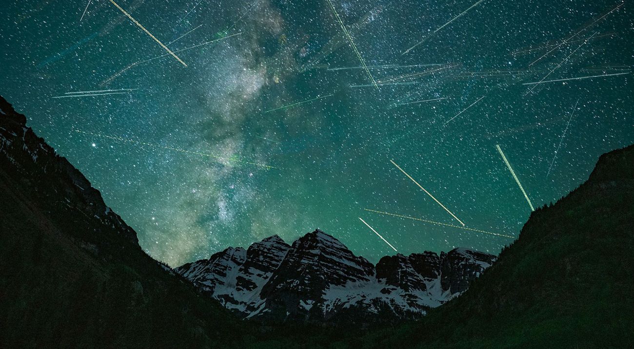 blue night sky with thousands of blurred stars over dark mountains