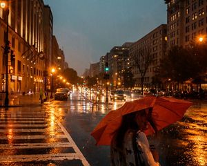 A person with a red umbrella on a rainy night in Washington, D.C.