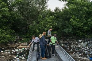 Cuatro hombres usan redes para extraer basura de la superficie del río.