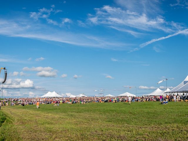 White tents on a green prairie prepare to host a symphony performance