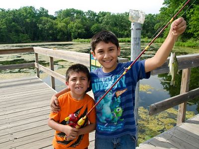 Two young boys hold up their catch from a fishing pier.