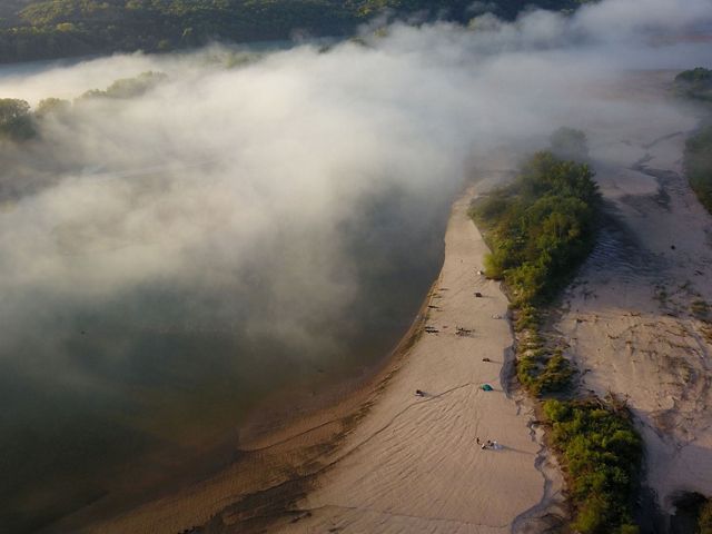 Aerial view of tents on a sandy river shore.