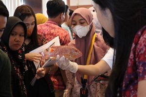 Several people gather around to look at a fish that one of them is holding in their hand.