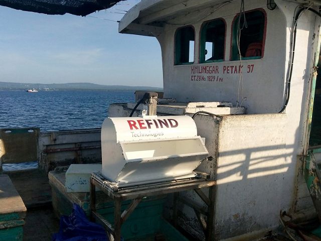 A machine labeled REFIND sits aboard a small fishing boat.