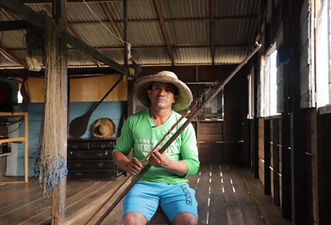 A man sits holding fishing poles.