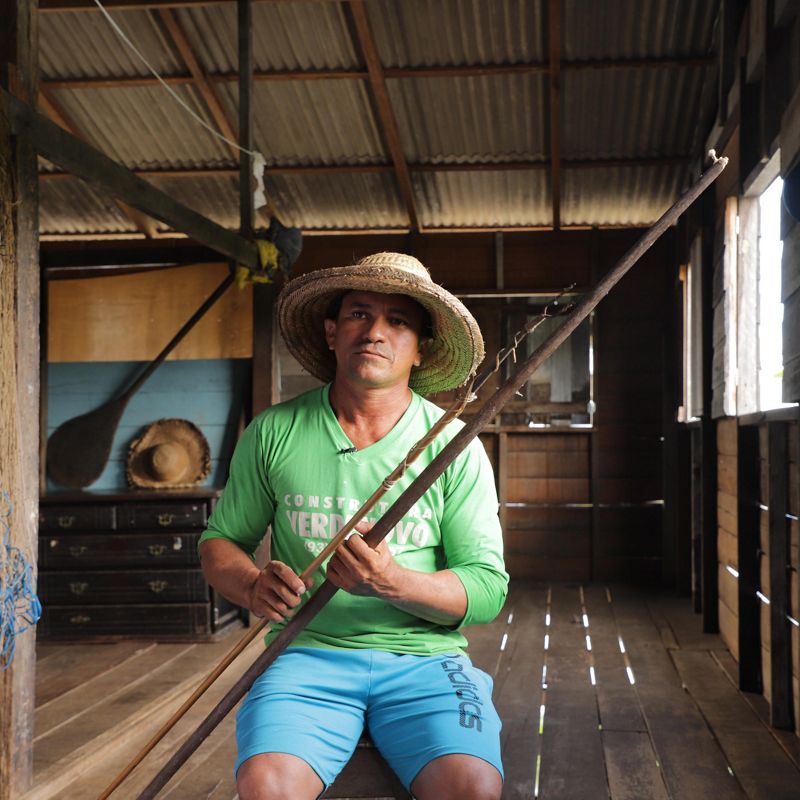A man sits holding fishing poles.