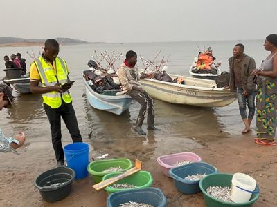 People standing or sitting on or near fishing boats.