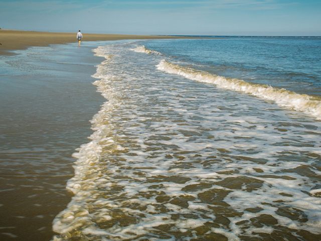 The sandy beach of the Atlantic with small calm waves lapping the shore.
