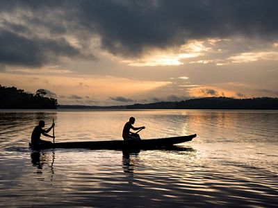 Two fishermen in a canoe at sunrise