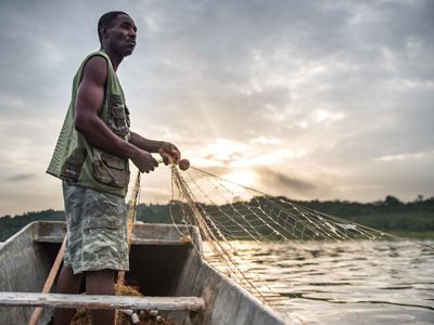 Man pulls a fishing net from a small boat
