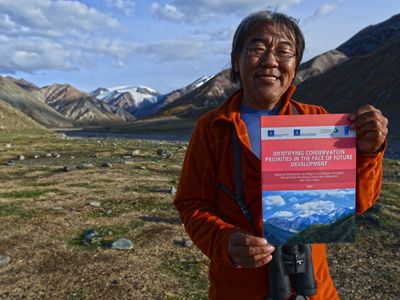 Portrait of Gala Davaa holding up a report about Western Mongolia.