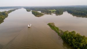 A small boat moves through a broad river.