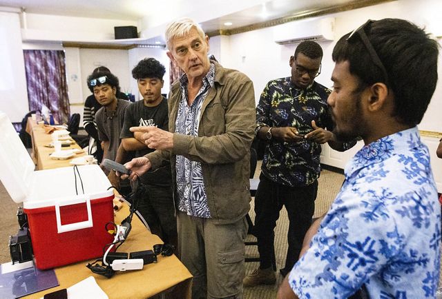 A person stands in a classroom and talks to students.
