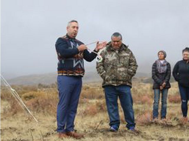 Photo of five people standing on open grasslands, with man gesturing while he speaks about the land.