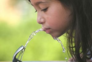 Girl drinking water from a fountain.