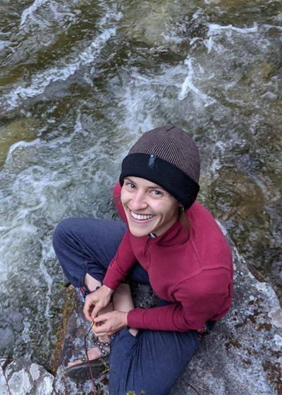 Candid portrait of Grace Peven sitting next to a river.