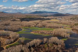 Green fields flooded by river water with mountains in the background.