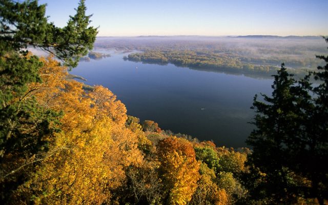 Brilliant autumn foliage viewed from a bluff overlooking a river.