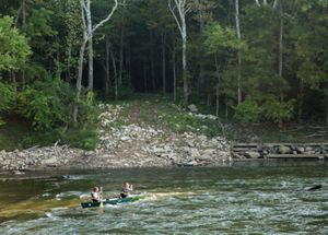 Two people on a canoe go over some light rapids in the Green River.