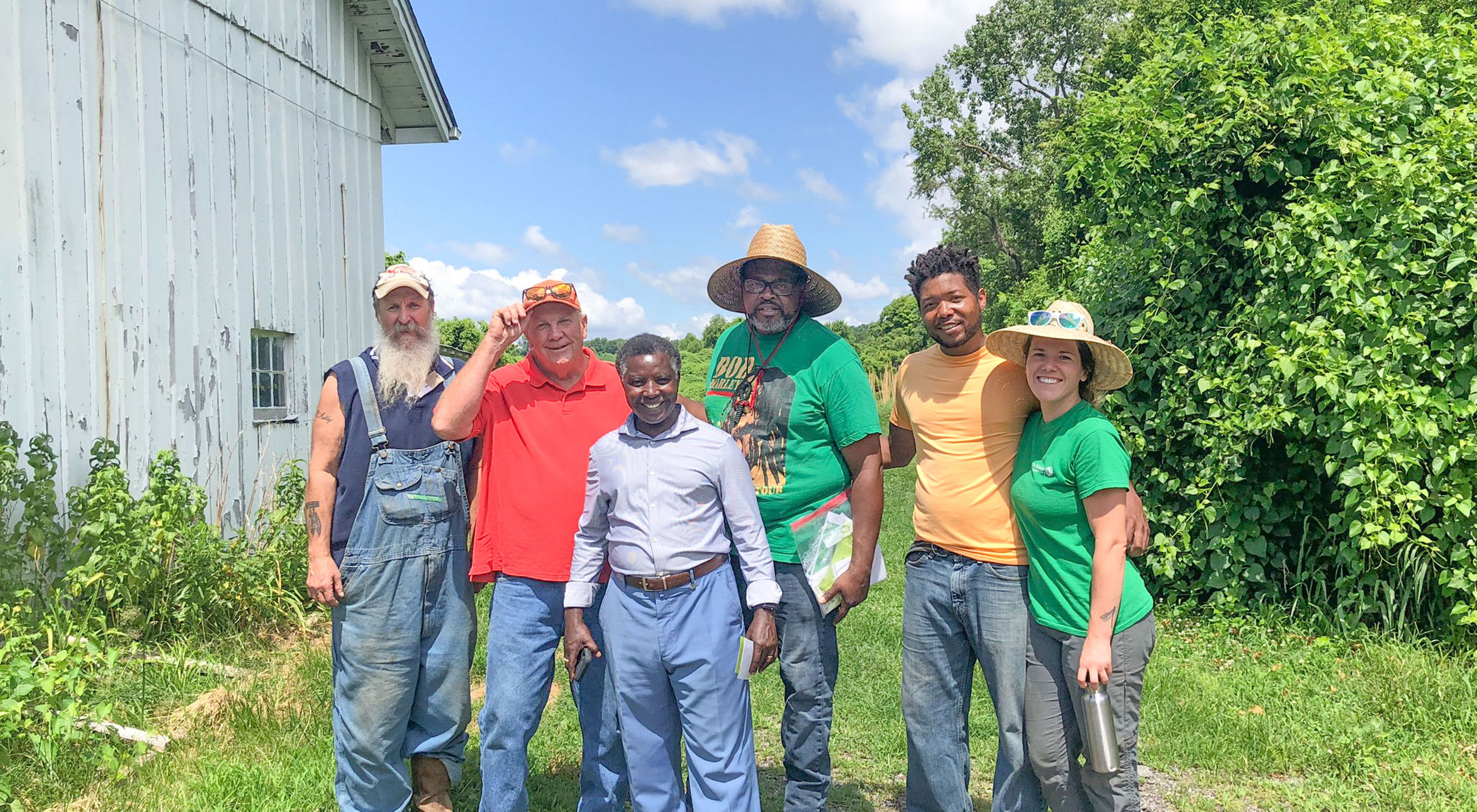 Pastor Bruce Carroll (back, center) of Green The Church visits with Rebecca Weaver (right), Pastor Paul (front, center) & Gibron Jones (2nd from right) at Confluence Farms.