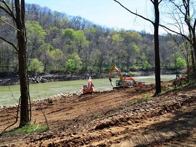 Construction equipment sits on a river bank.