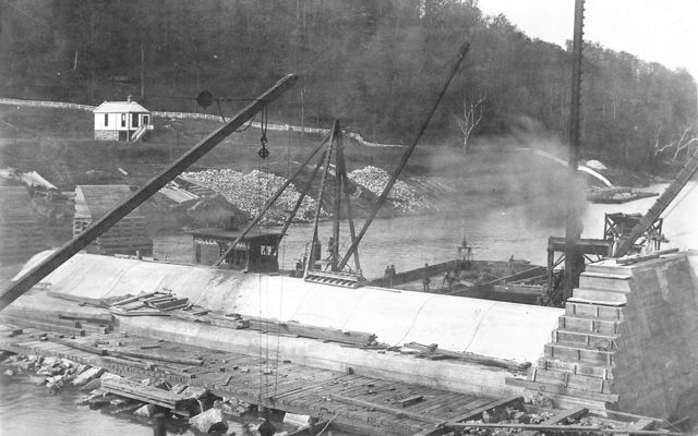 Historical black-and-white photo of cranes constructing the dam.