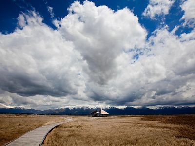 A boardwalk leading up to a pavilion on a field of wetlands.