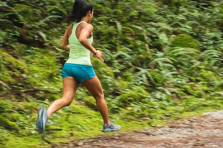 A person runs on a trail in a forest.