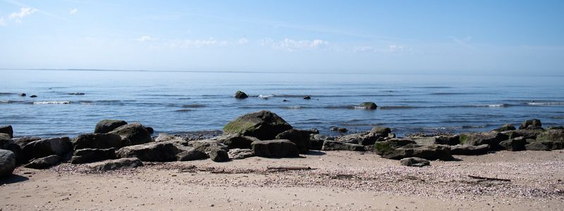 A green-blue ocean meets up with a rocky beach.