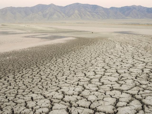 A dry, cracked-earth lakebed with mountains in the background.