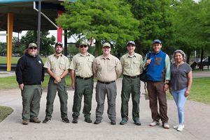 A group of six men and one woman pose as a group in a park.