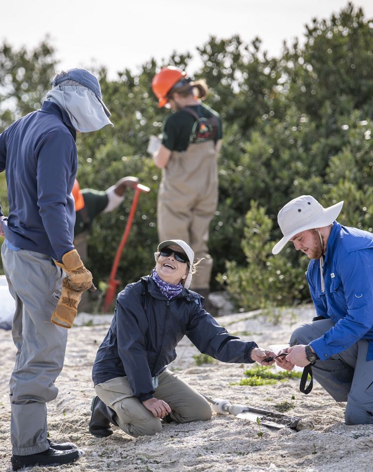 Three people working on a beach.