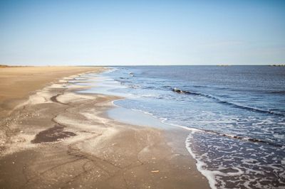 Blue-gray ocean waters meet a sandy beach.