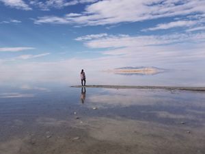 A person stands on a sandbar in the middle of the Great Salt Lake.