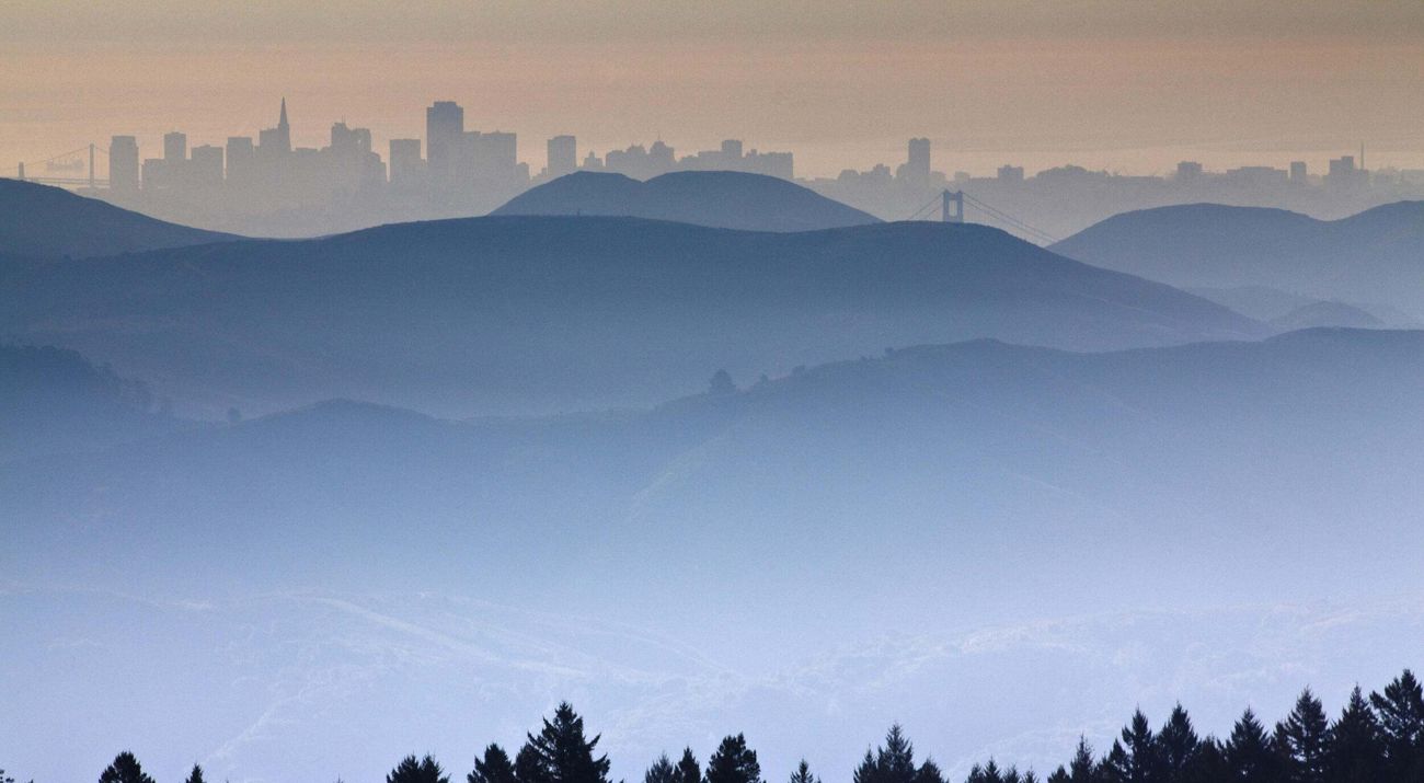 Rolling hills in the foreground with the silhouette of the skyline of San Francisco in the background.