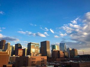 Skyline of Denver under blue sky with broken clouds.