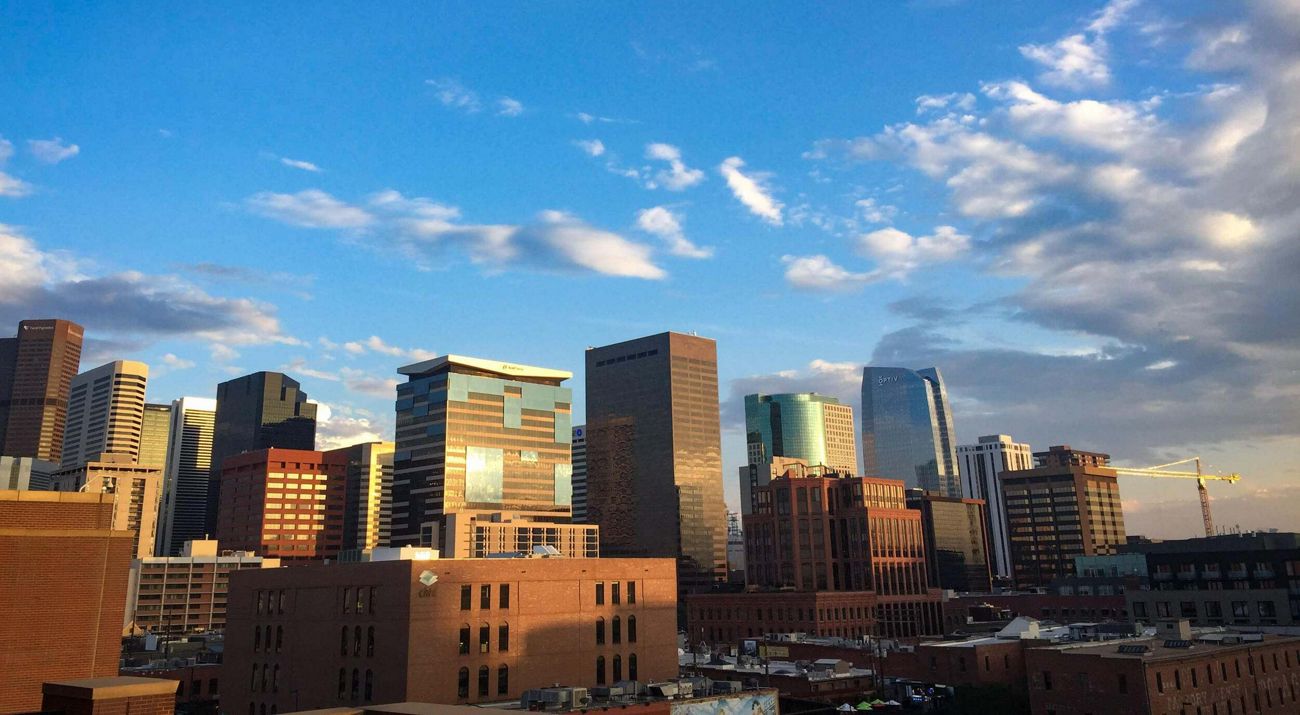 Skyline of Denver under blue sky with broken clouds.
