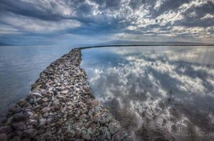 Long, curving row of rocks forms a fish pond in a large body of water.