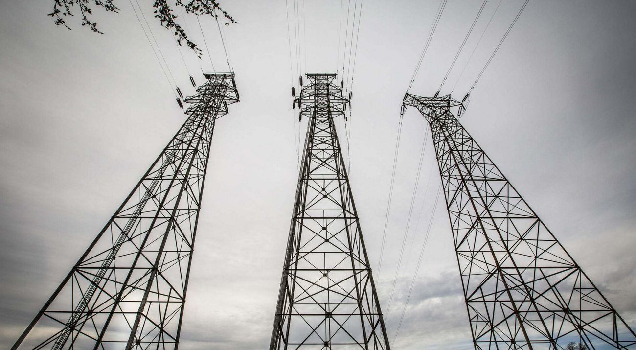 Looking up at electrical transmission towers.