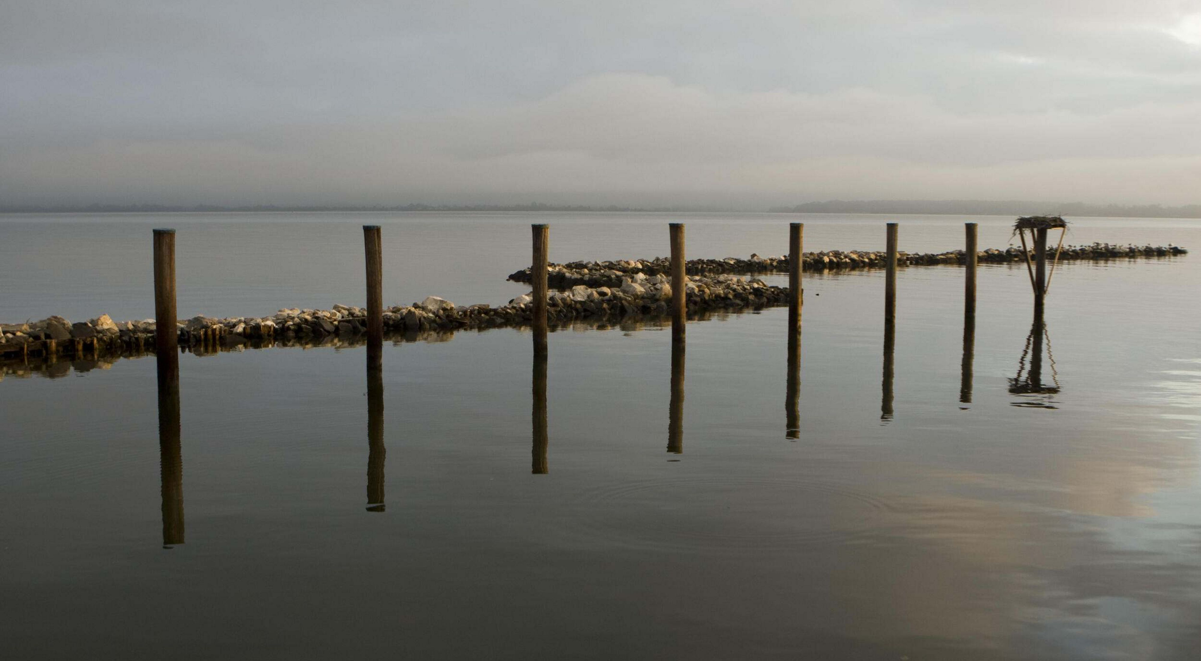 A wooden dock expands out into calm waters.