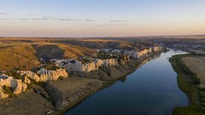 Chalky white cliffs and rolling terrain rises from the banks of a river.