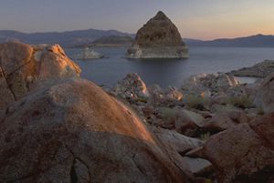 Boulder and rock formations surrounding a lake in an arid setting.