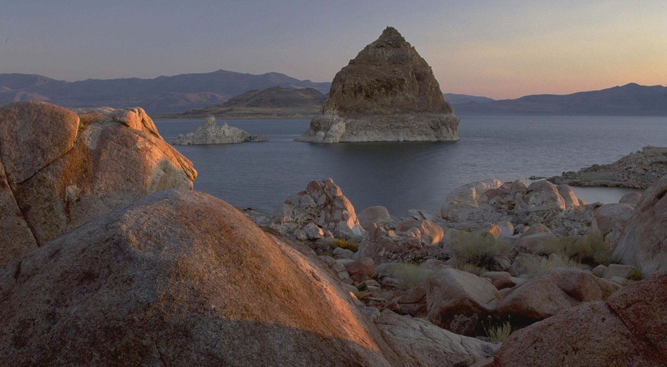 Boulder and rock formations surrounding a lake in an arid setting.