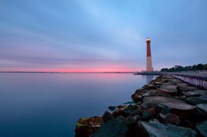 A lighthouse positioned alongside a still body of water.