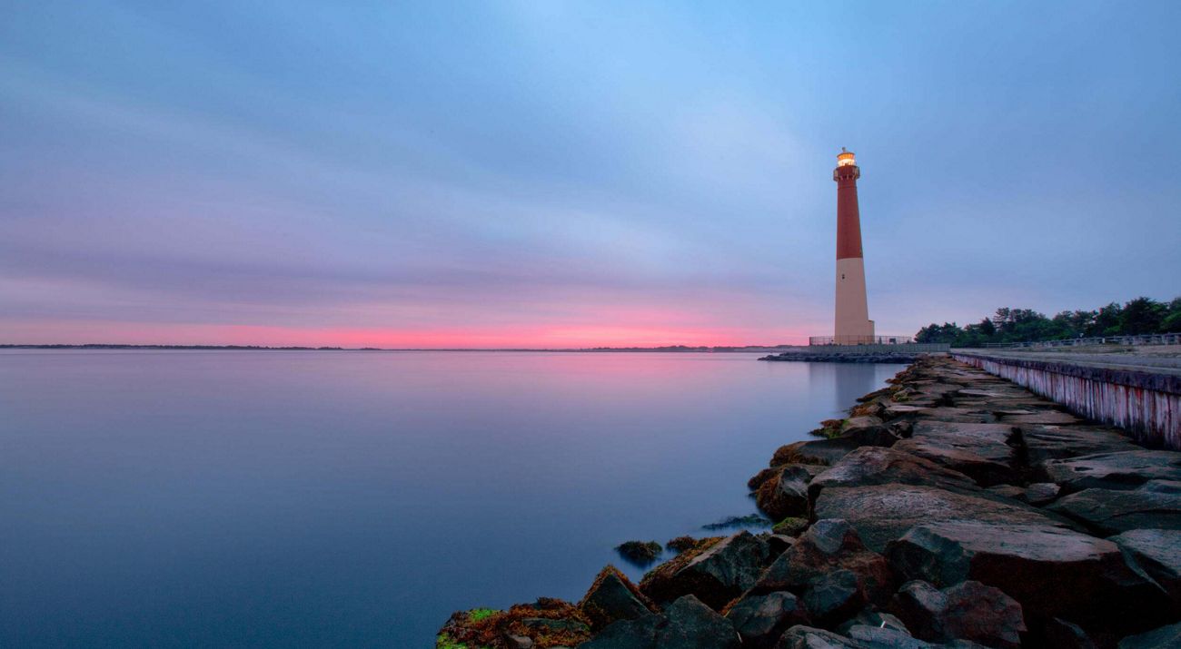 A lighthouse positioned alongside a still body of water.