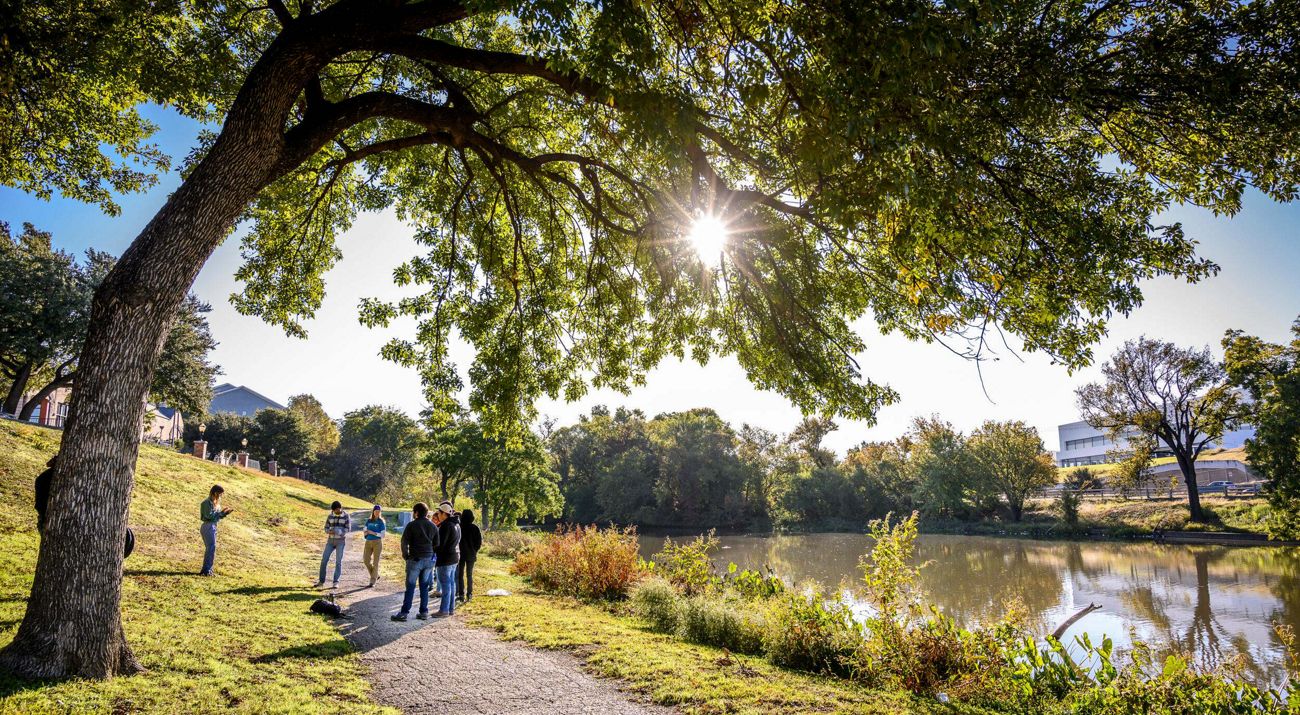 Volunteers gathered on a path alongside a pond at a park.