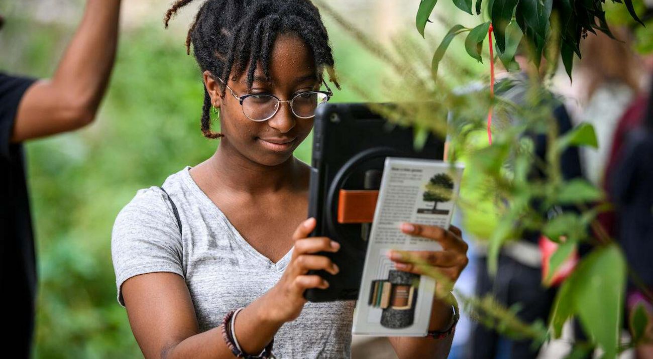 A young woman holding and reading an iPad.