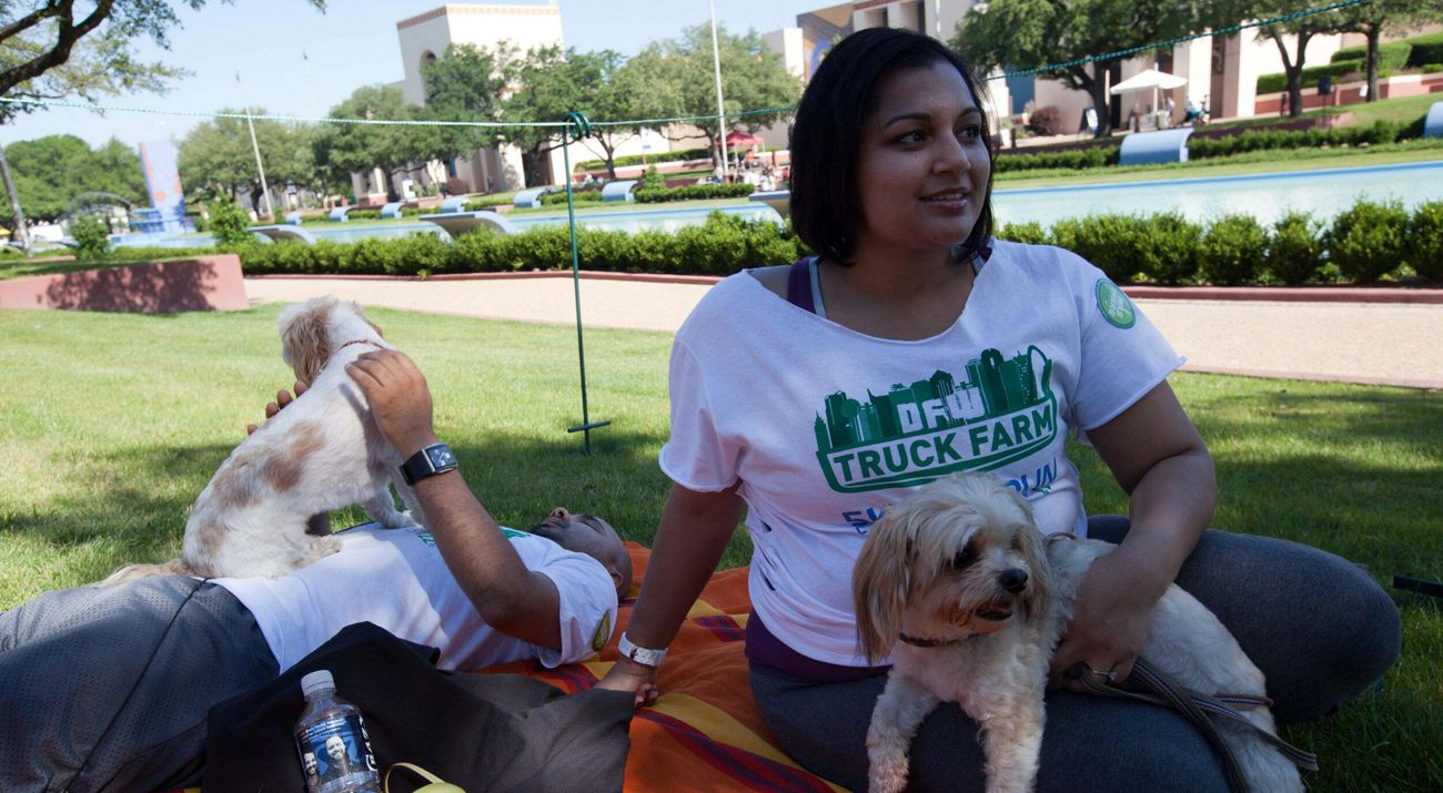 A couple sits with their dogs on the grass at a park.