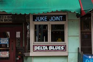 Window at a bar with an illuminated sign that reads, Juke Joint.